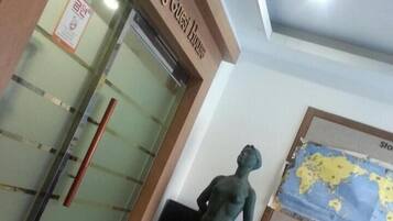 A lobby with a glass door entrance labeled 'Hyaseong Guest House', a map on the wall, and a statue of a person.