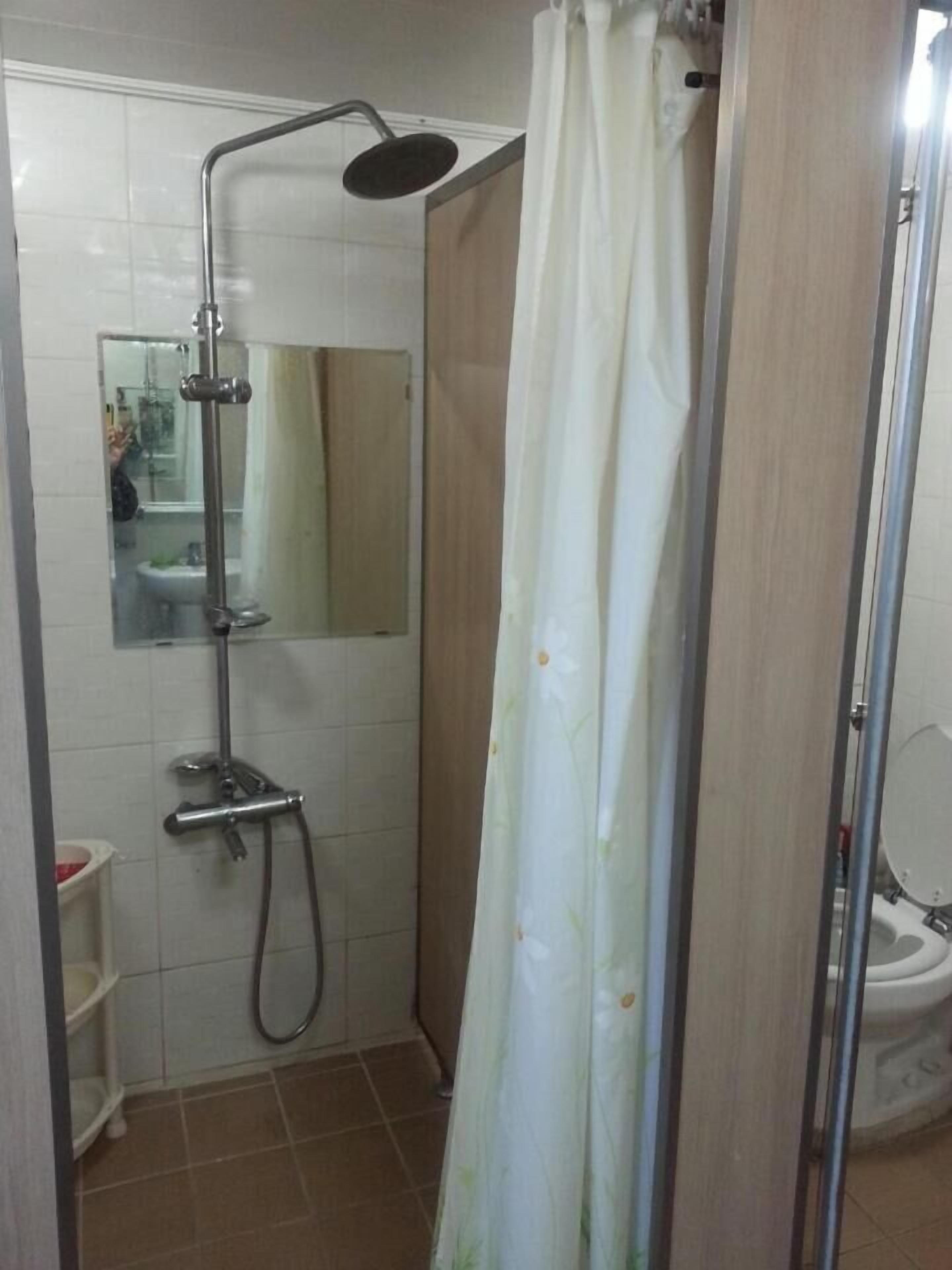Eine Dusche mit Handbrause und spiegelverkleinertem Bereich.