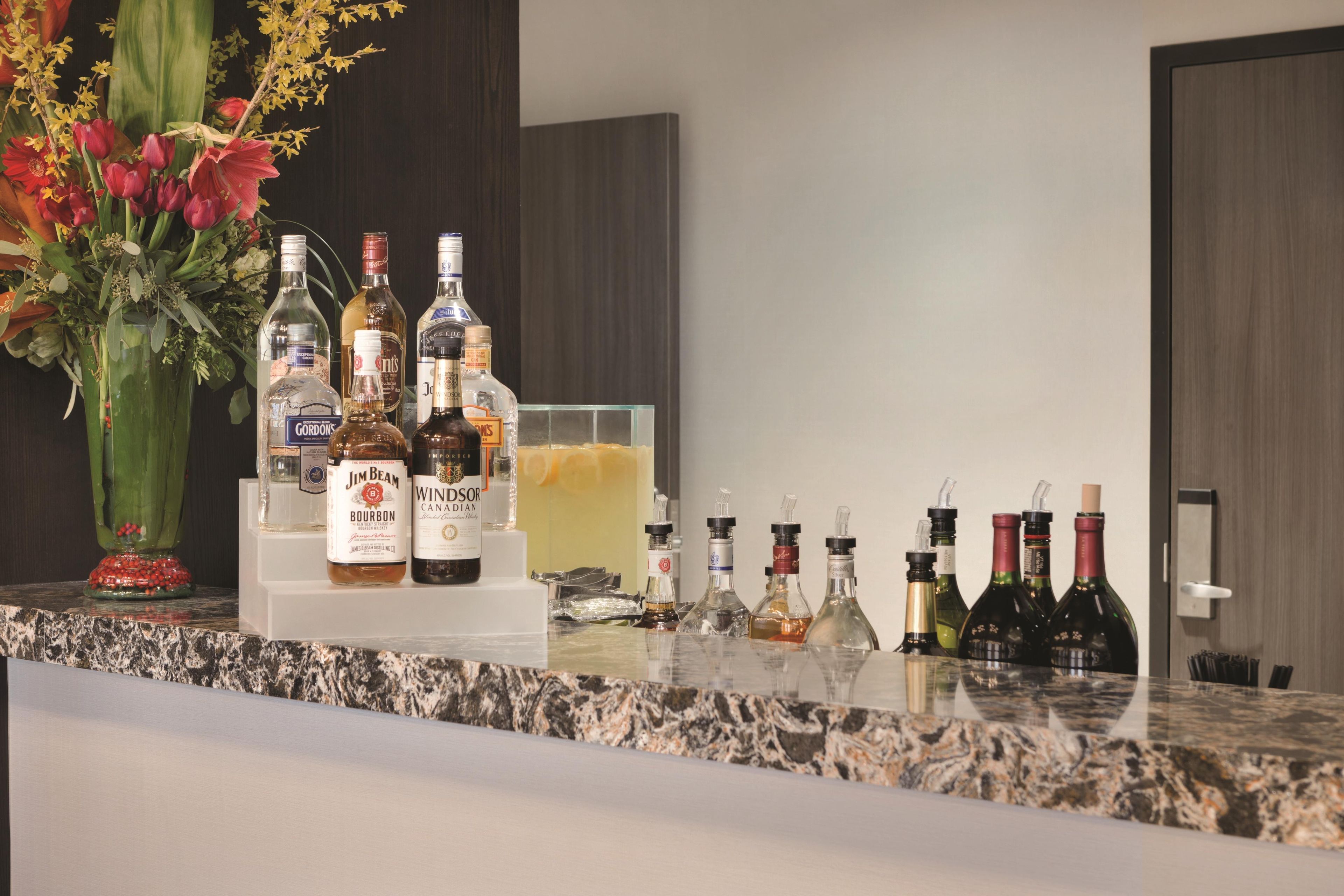 Una zona de bar con botellas de licor, un florero y un recipiente de vidrio.