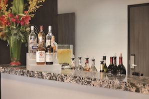 Eine Bar mit Spirituosenflaschen, einem Blumenstrauß und einem Glasgefäß.