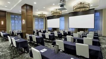 A conference room with rows of tables, chairs, and large screens.