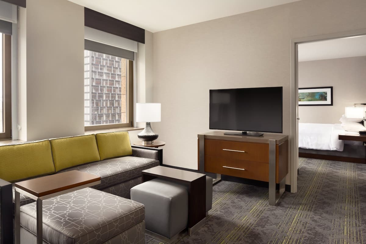 Una habitación de hotel con sofá, televisión, escritorio y cama.