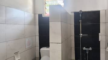 Ein Badezimmer mit Toilette, Dusche und einem kleinen Fenster.