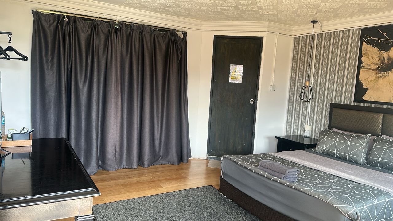 A bedroom with a bed, bedside tables, a desk, and a hanging light fixture.