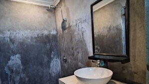 Un baño con un lavabo blanco, un espejo y suelo de baldosas.