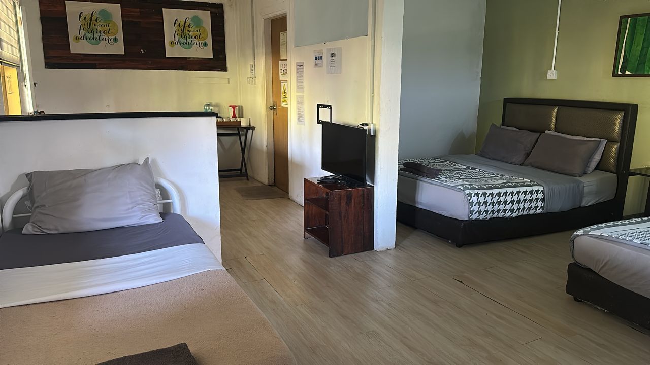A room with two beds, a TV stand, and a desk.