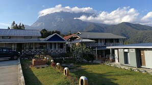Un hotel con varias edificaciones, una zona de estacionamiento y montañas al fondo.