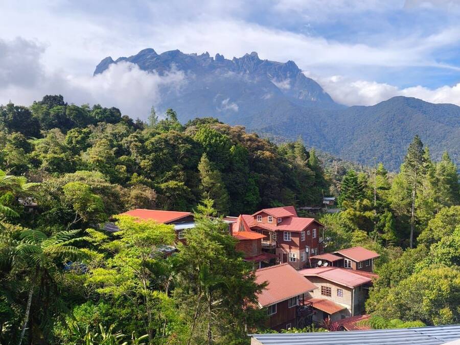 A mountainous landscape with a house featuring a red roof and multiple levels.