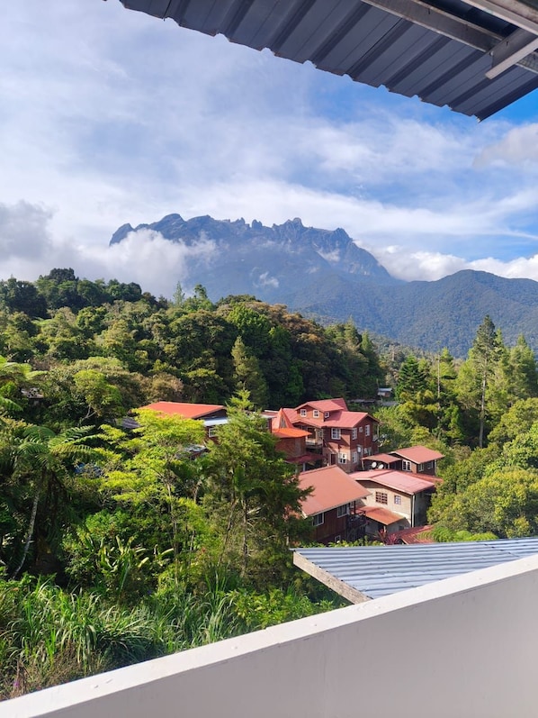 A mountainous landscape with a house featuring a red roof and multiple levels. - Ceaser's Place (Ranau)