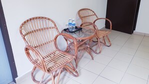 A room with a glass-top table and two wicker chairs. There are two bottles of water and a glass on the table. - Champcity Hotel (Kuantan)