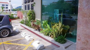 A building with a glass entrance, a parking area with a car, and a signboard. - Champcity Hotel (Kuantan)