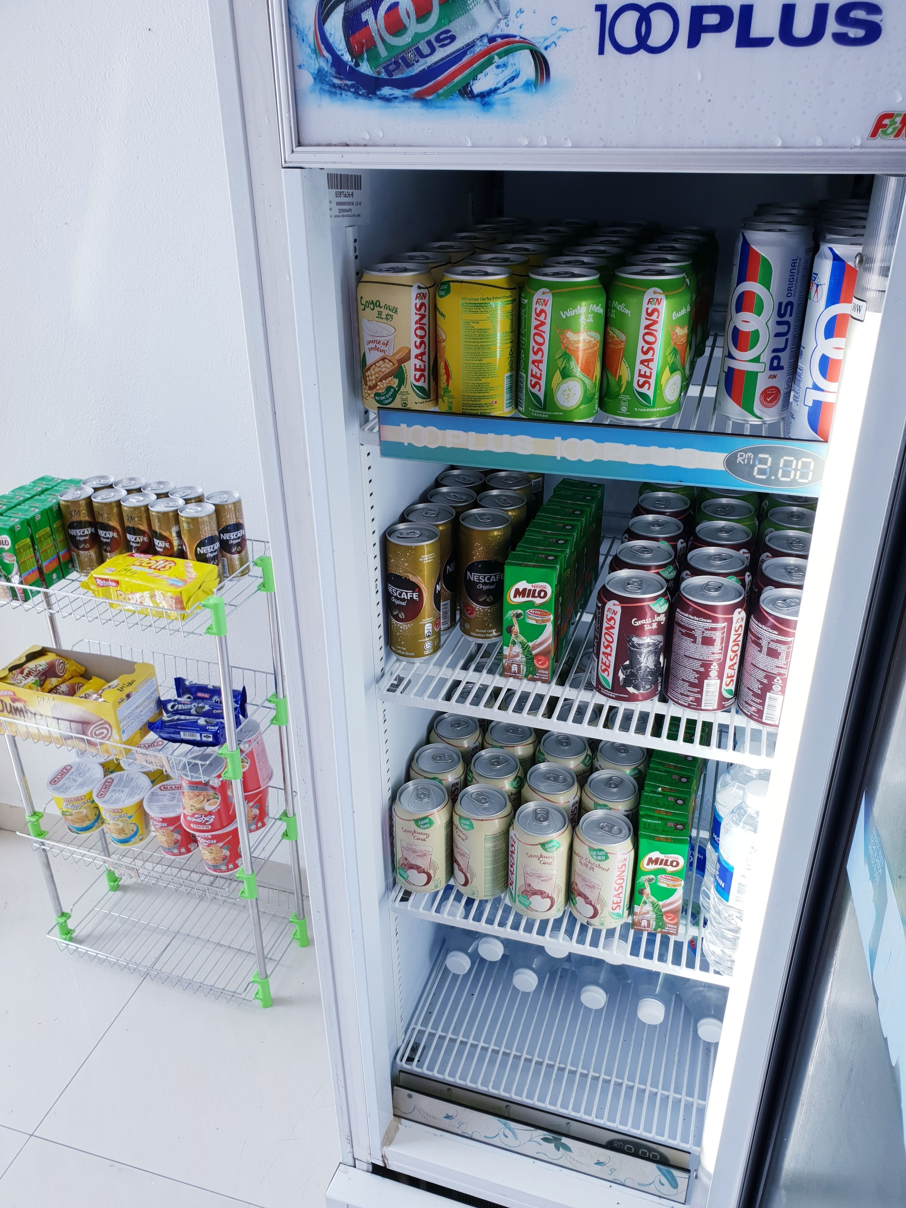 A beverage vending machine stocked with various drinks including Nescafé, Milo, and 100 PLUS.