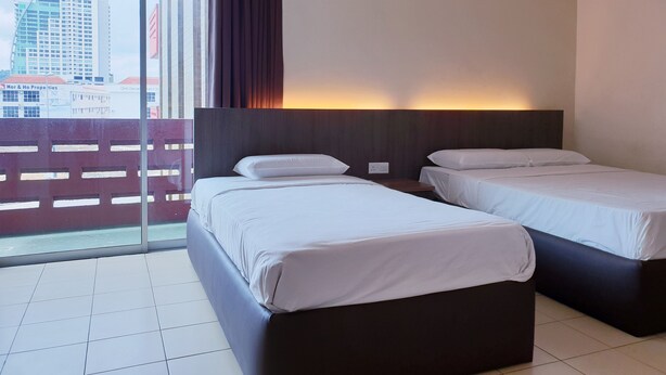 A hotel room with two beds, a large window, and a view of buildings outside. - Champcity Hotel (Kuantan)