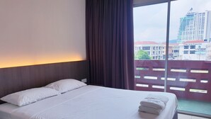A hotel room with a large bed, a window with curtains, and a view of a cityscape. - Champcity Hotel (Kuantan)