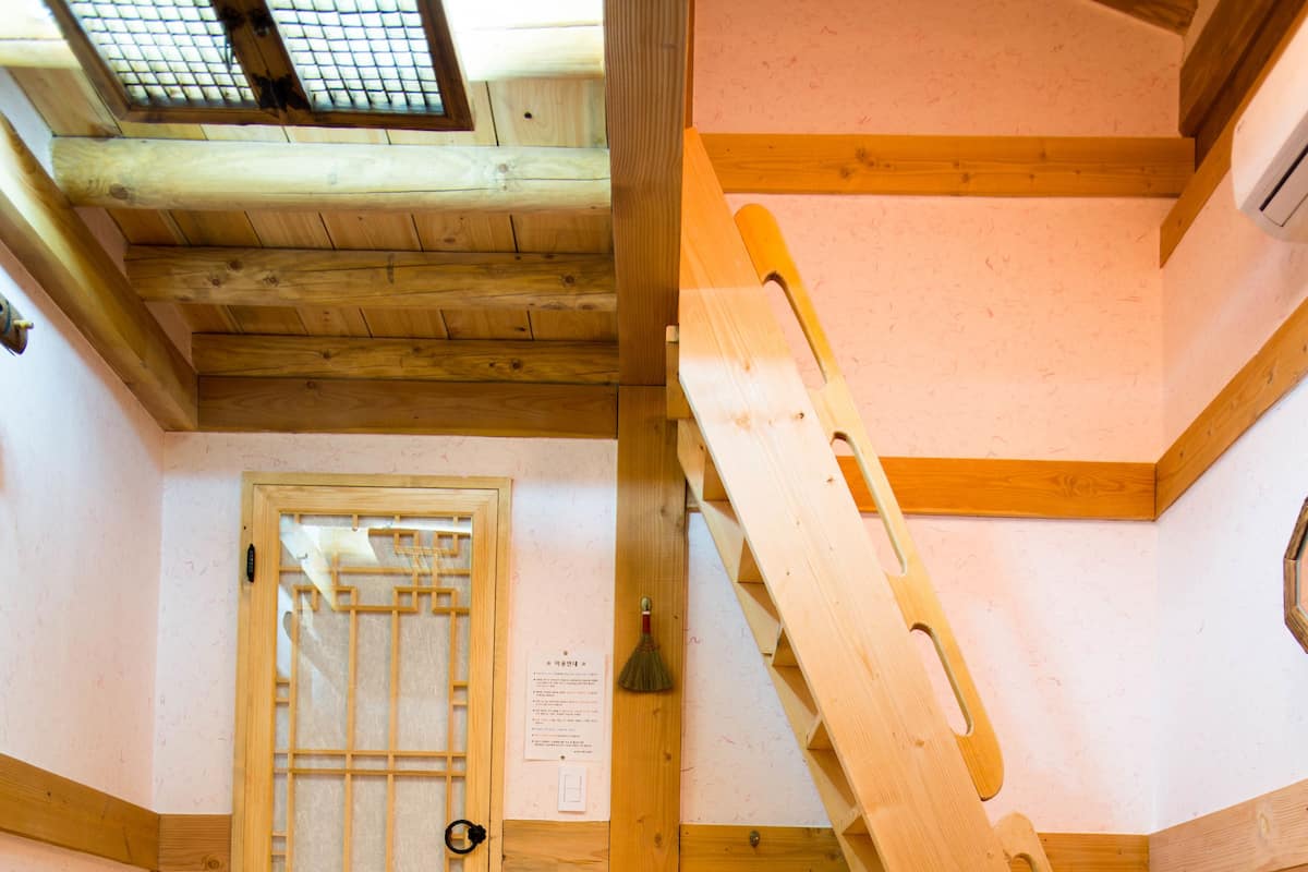 A wooden interior with a staircase, a traditional wooden door, and a stack of towels.