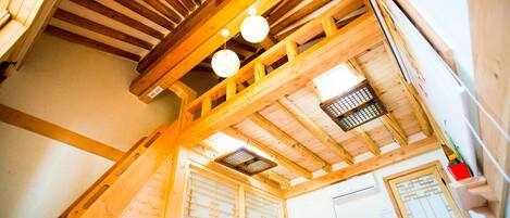 Een houten interieur met een hoge plafond, een trap en een aan de muur bevestigde televisie.