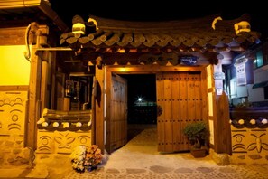 A traditional wooden gate with a tiled roof, leading to a building with a stone pathway.