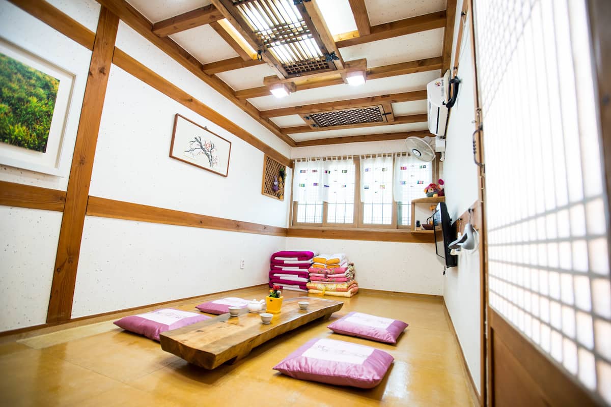 A traditional Japanese room with tatami flooring, a low wooden table, and a futon bed.