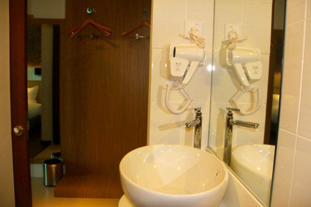 Un baño con un espejo grande, dos secadores de pelo montados en la pared y un lavabo.