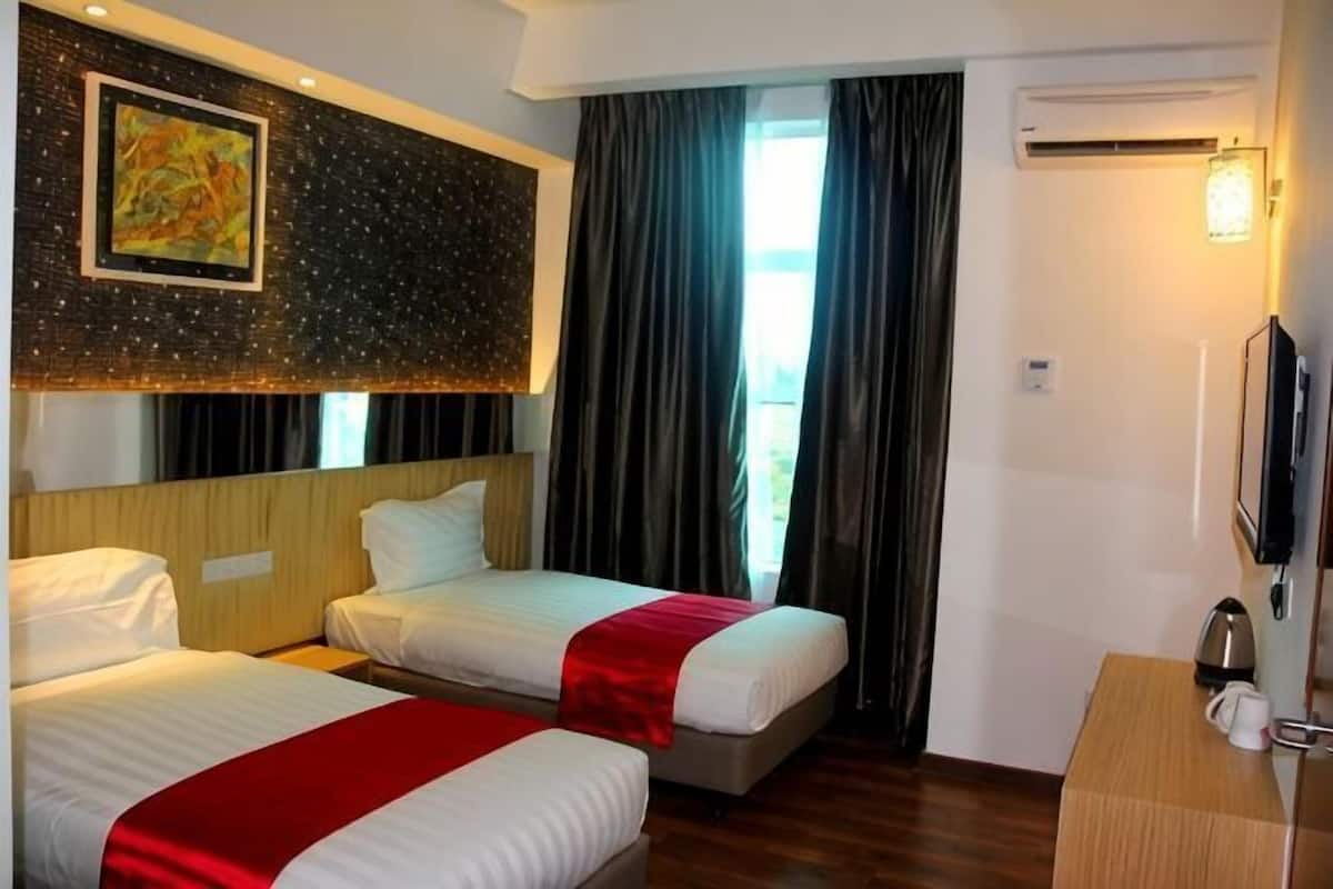 A hotel room with two beds, a desk, a TV, and a large window with curtains.