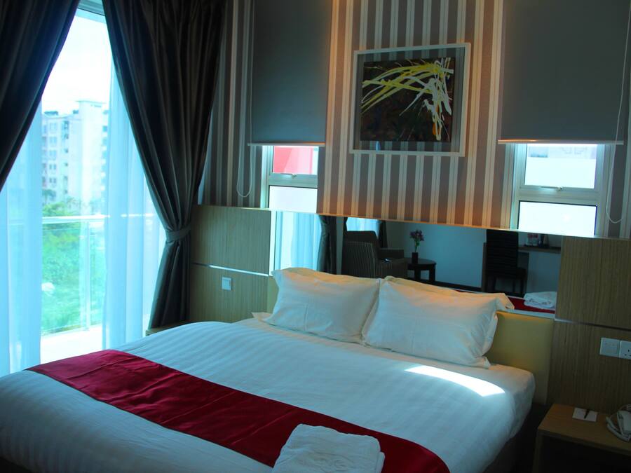 Habitación de hotel con una cama grande, una manta roja, un teléfono y un cuadro en la pared.