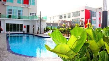 A swimming pool with a tiled edge, surrounded by lounge chairs and potted plants.