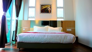 Une chambre d’hôtel moderne avec un grand lit, un téléviseur à écran plat et un tableau au-dessus du lit.