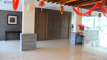 A spacious lobby with a modern reception desk, a large wooden door, and red decorations.