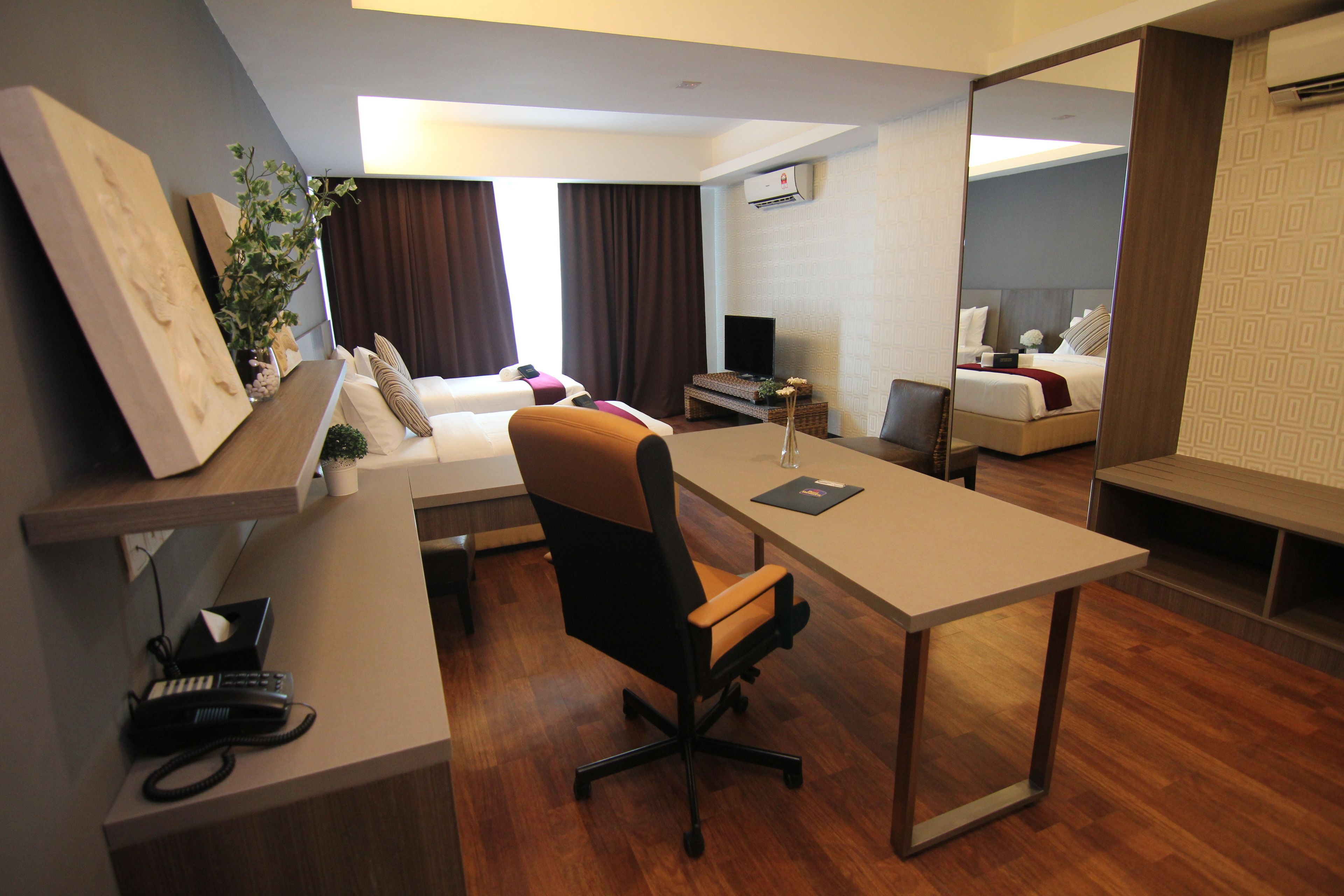 Una habitación de hotel moderna con escritorio, silla de oficina, sofá y un espejo grande.