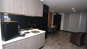 Cozinha moderna com frigorífico embutido, pia e máquina de café. Há uma área de refeições com mesa e cadeiras.