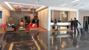 Um lobby moderno com balcão de recepção, áreas de estar e piso lustroso.