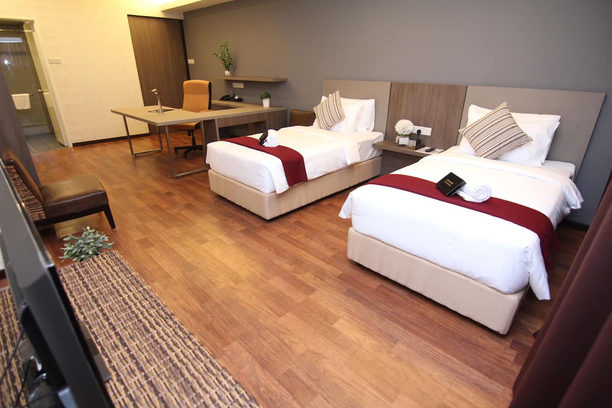 A hotel room with two beds, a desk, a chair, and a small table.