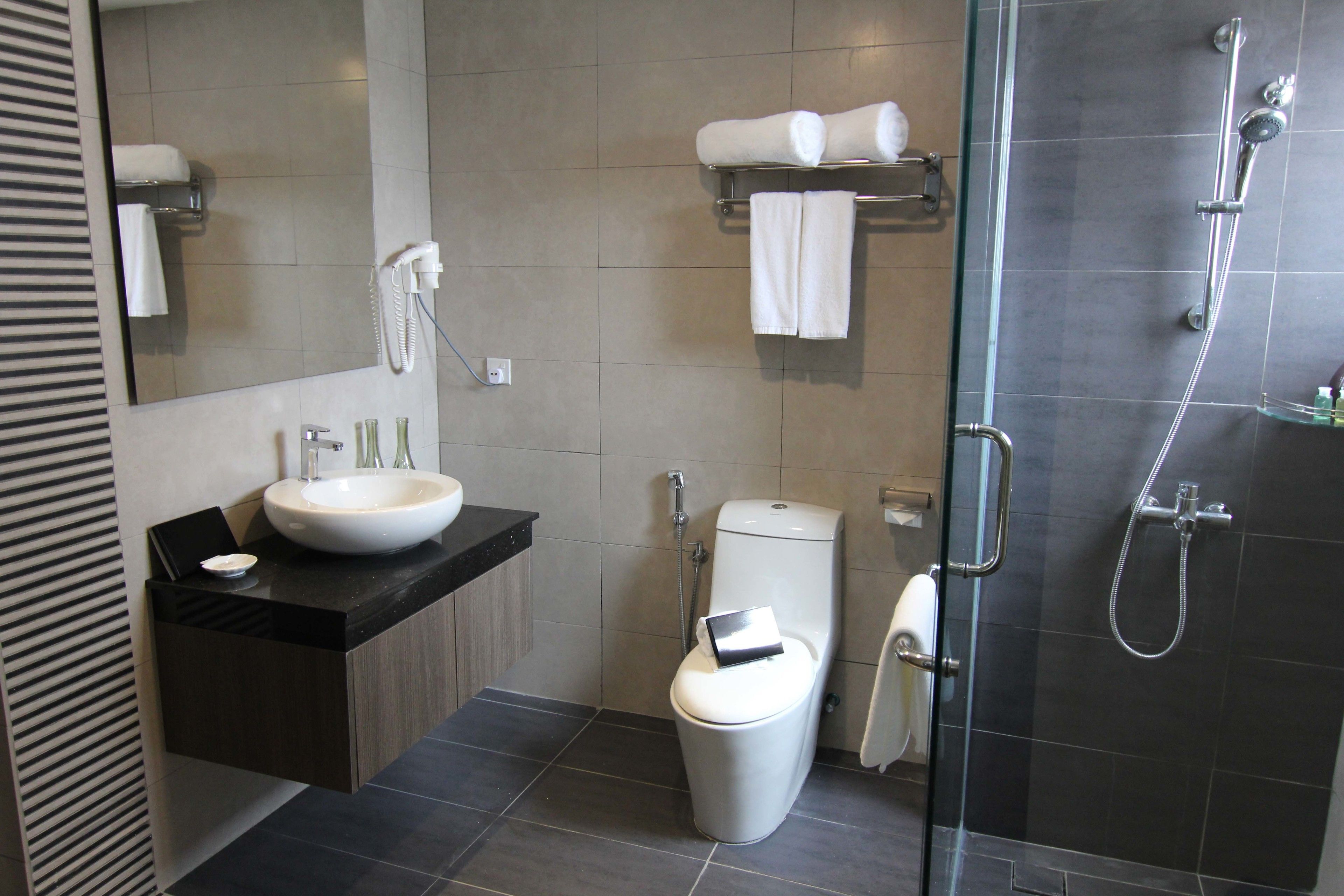 Ein modernes Badezimmer mit einem großzügigen Waschbecken, Toilette und einer Duschkabine aus Glas.