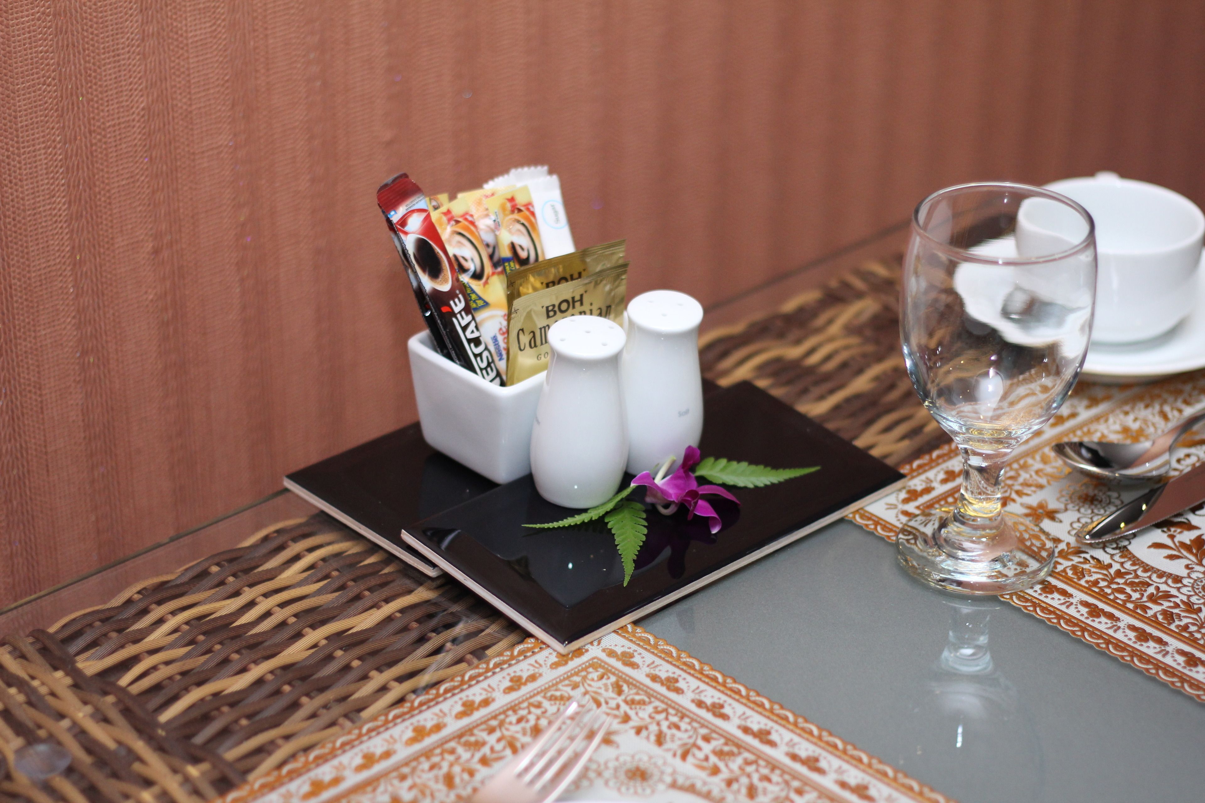 Una mesa servida con un vaso, saleros y pimenteros, una servilleta y un menú.