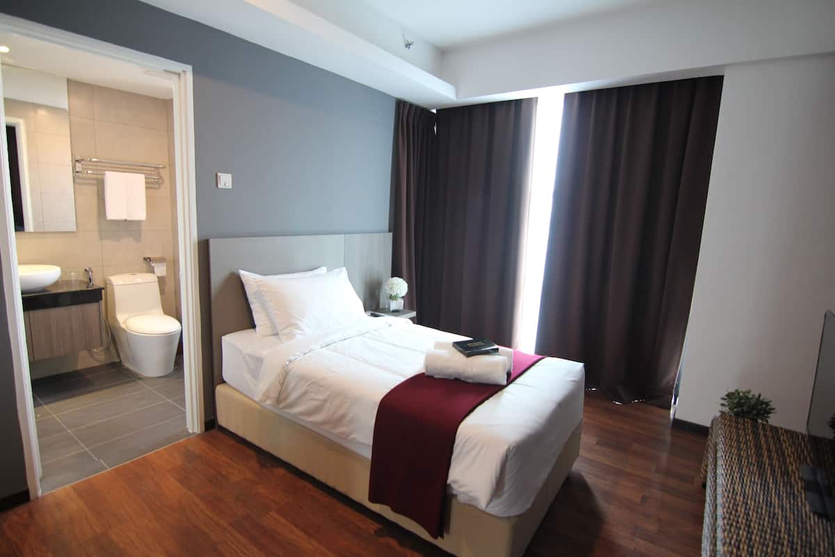 A modern hotel room with a large bed, a bathroom with a sink and toilet, and a view of the outdoors.