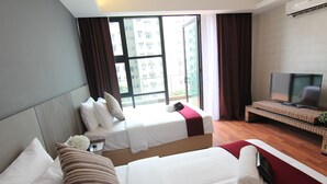 Quarto de hotel com duas camas, televisão e uma janela grande com cortinas.