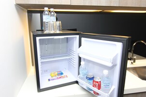 Ein offener Kühlschrank mit Wasserflaschen, einer Cola und einer Tüte Snacks.
