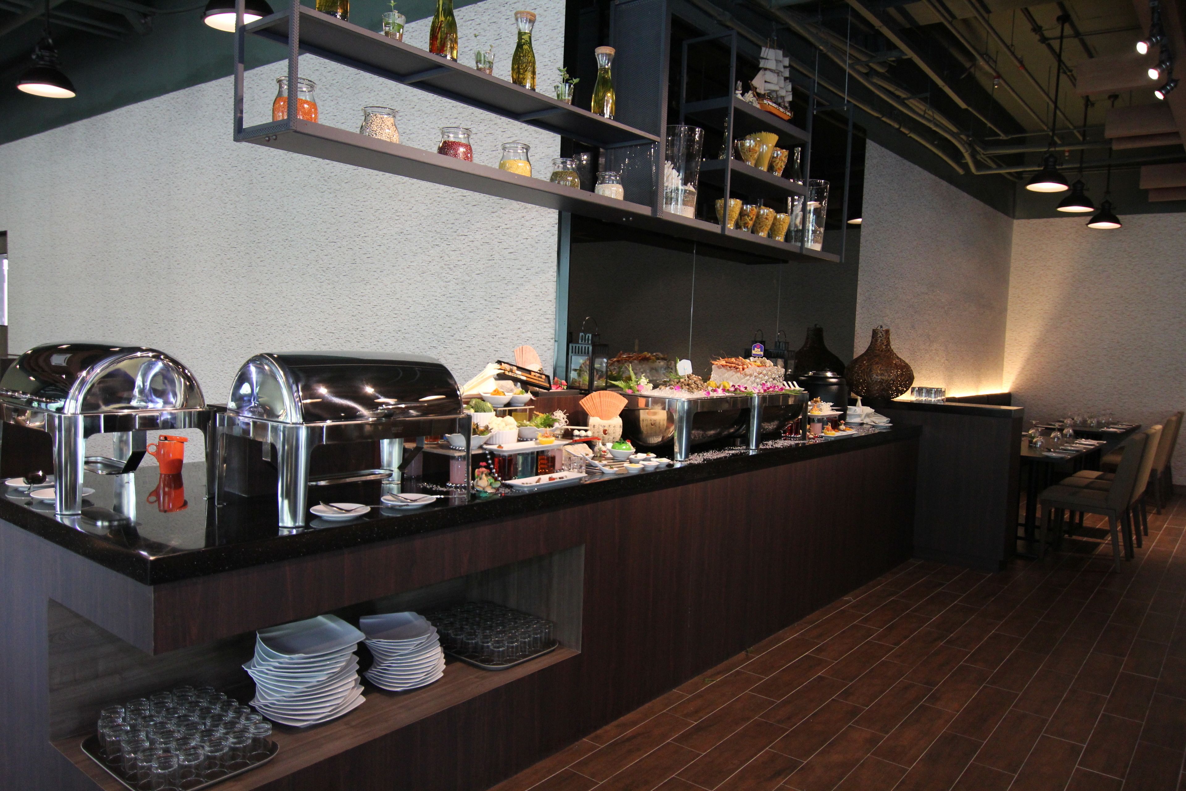 Un buffet proposant une variété de plats, une machine à café et un espace détente avec des tables et des chaises.