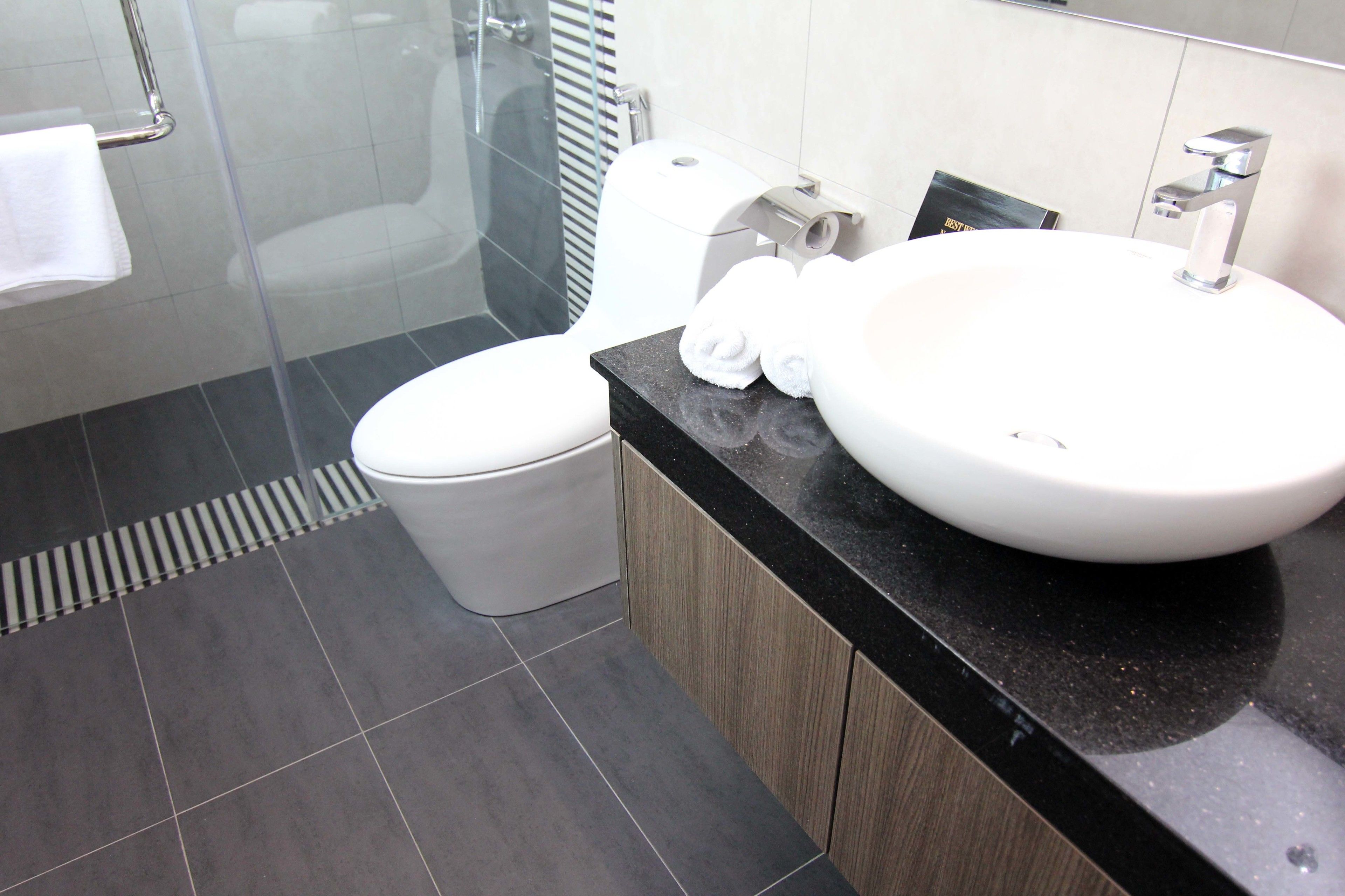 A modern bathroom with a large white sink, a toilet, and a glass shower enclosure.