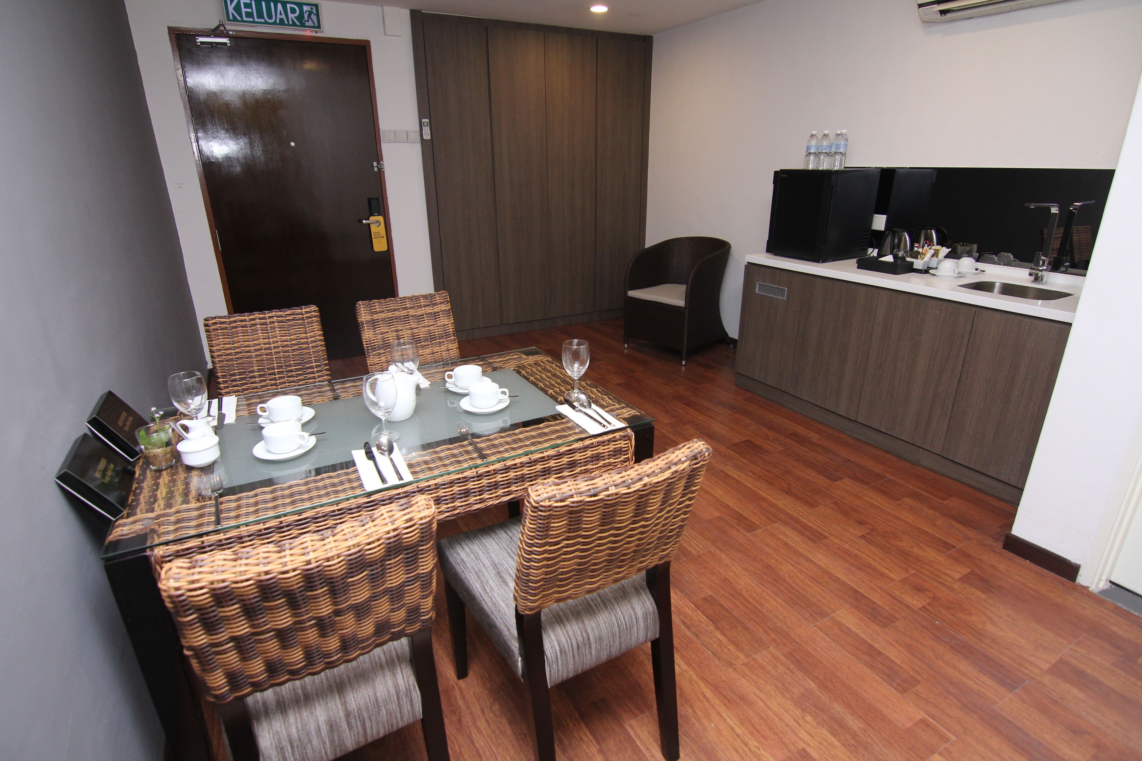 A dining area with a glass-top table, wicker chairs, and a kitchen area with a sink and cabinets.