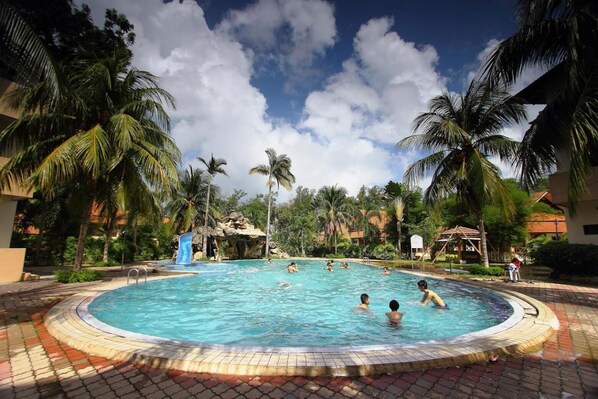 Una piscina rodeada de palmeras y una formación rocosa.