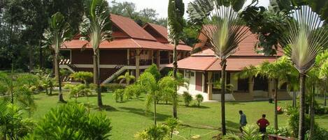 A resort with multiple buildings, a well-maintained lawn, and palm trees.