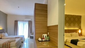 Une chambre d’hôtel avec deux lits, une cloison en bois, une petite kitchenette et une salle de bain avec douche.