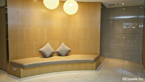 A modern reception area with a curved bench, two spherical pendant lights, and a wooden wall. - The Haven by JetQuay (Singapore)