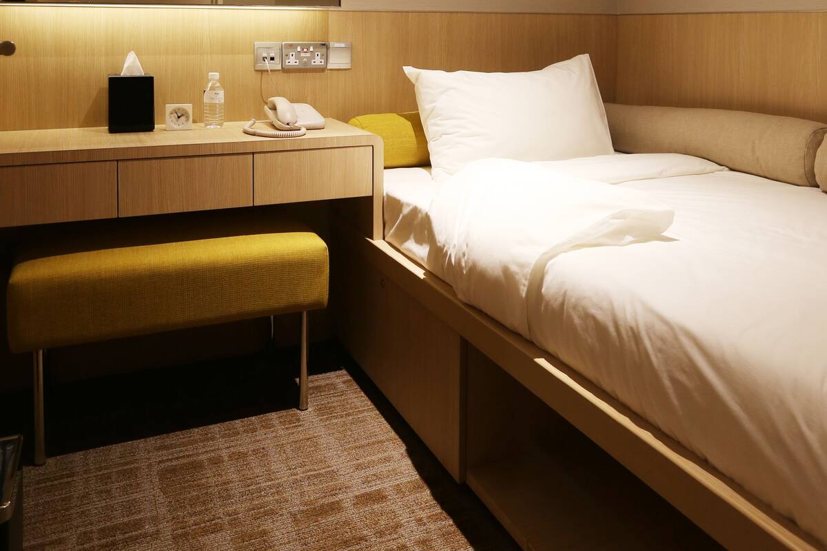Ein Hotelzimmer mit Bett, Nachttisch, Spiegel und einer Bank.
