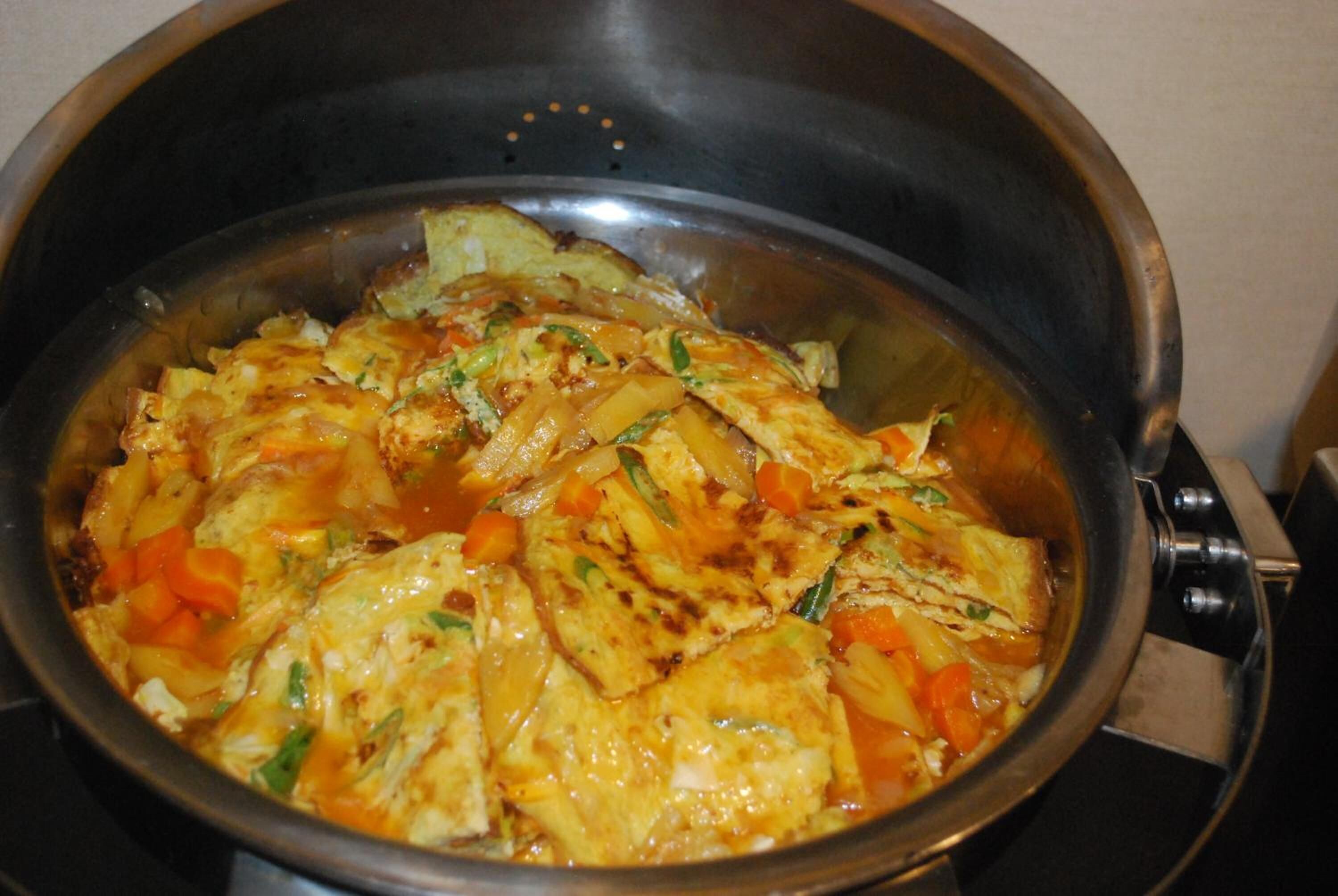 Una olla con un plato de tofu, verduras y salsa.