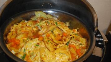 Una olla con un plato de tofu, verduras y salsa.