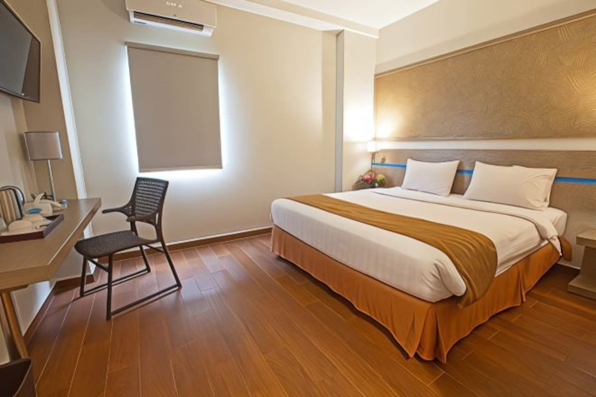 Una habitación de hotel con una cama, un escritorio, una silla y una ventana.