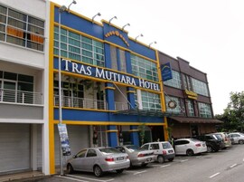 Un hotel con fachada azul y amarilla, varios pisos y un estacionamiento con varios coches.
