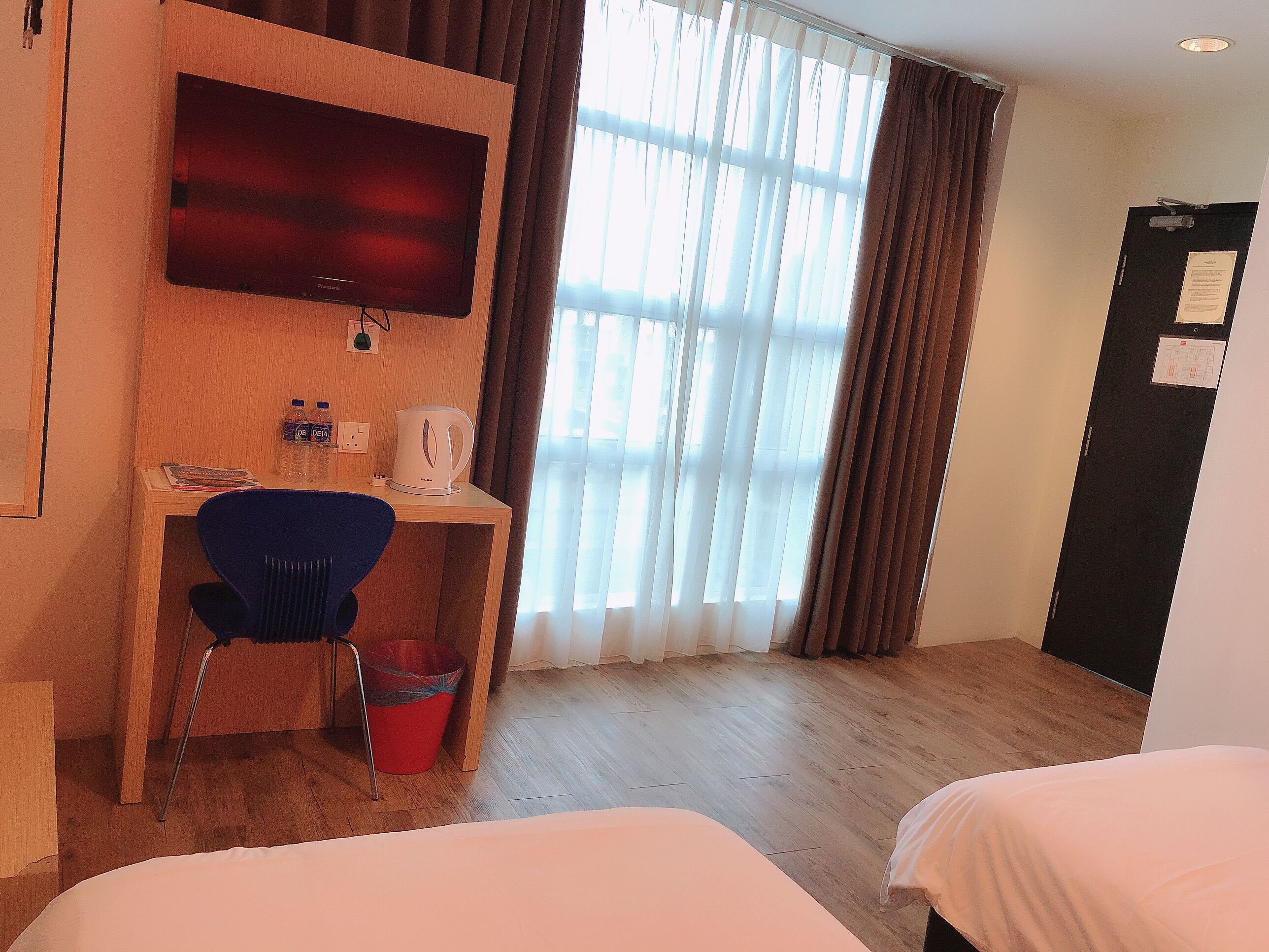 Una habitación de hotel con un escritorio de madera, una silla, una cama y un televisor.